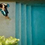 Overhead view of woman in robe standing on top step of hotel pool