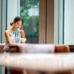 Young Asian women tourist sits at hotel bar and has a drink. Business travel, Vacation.